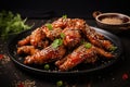A mouthwatering image of chicken wings coated in sesame seeds and served on a black plate, Delicious crispy BBQ chicken wings with