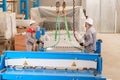 Move the crane with beam. Workers adjusts the machine in the warehouse. the production of ventilation and gutters. Tool Royalty Free Stock Photo