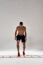 Move forward. Full length shot of young athletic man training on agility ladder drill isolated over grey background Royalty Free Stock Photo