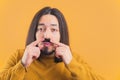 Movember - medium closeup young European man touches fake moustache yellow background copy space isolated studio shot Royalty Free Stock Photo