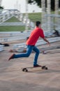 In movement boy walking on a longboard with a red t-shirt and blue jeans