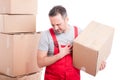 Mover guy holding cardboard box making heart attack gesture