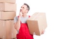 Mover man holding cardboard box making thinking gesture