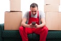 Mover man sitting on couch holding smartphone Royalty Free Stock Photo