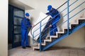 Movers Carrying Refrigerator While Climbing Steps Royalty Free Stock Photo