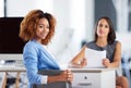 The movers and shakers of the office. Portrait of two smiling young businesswomen sitting together at a desk in an Royalty Free Stock Photo