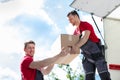 Movers Unloading A Moving Van And Passing A Cardboard Box Royalty Free Stock Photo