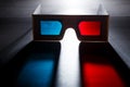 Movie at cinema concept. 3D glasses with red and blue lenses with soft colored shadow on dark background. Royalty Free Stock Photo