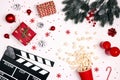 Movie clapper board with Christmas decorations, gifts and popcorn on white background Royalty Free Stock Photo