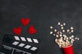 Movie clapper board, popcorn and hearts on black background. Valentine`s Day movie concept