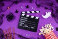 Movie Clapper board in spider webs, spiders, ghost, eyes on purple Lilac Background.