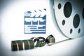 Movie clapper and 35 mm film roll on white Royalty Free Stock Photo