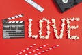 Movie clapperboard, film strip, videotapes, straws and the word love from popcorn lie on a red Royalty Free Stock Photo