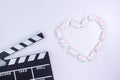 Movie clapperboard with heart shaped from twisted marshmallows. Valentine\'s day concept. Love. White background with twisted