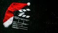 Movie clapperboard with Santa`s hat and sparkling glitter with space for text. Christmas movies concept