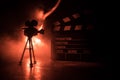 Movie concept. Miniature movie set on dark toned background with fog and empty space. Silhouette of vintage camera on tripod Royalty Free Stock Photo