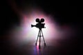 Movie concept. Miniature movie set on dark toned background with fog and empty space. Silhouette of vintage camera on tripod Royalty Free Stock Photo