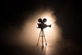 Movie concept. Miniature movie set on dark toned background with fog and empty space. Silhouette of vintage camera on tripod Royalty Free Stock Photo