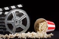 Movie film reel and film clapper with popcorn box on black Royalty Free Stock Photo