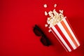 Movie night concept - pop corn, glasses, bright red background