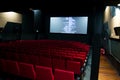 Movie screen and red chairs inside of a cinema