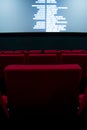 Movie screen and red chairs inside of a cinema