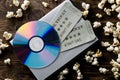 Movie tickets, DVD or blu ray disc and popcorn on dark wooden table background. Home theatre movie or series night concept. Flat
