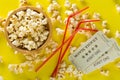 Movie tickets, soda drink plastic straws and popcorn on yellow table background. Home theatre movie or series night concept. Flat
