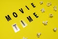 Movie Time text lettering with scattered salty popcorn on yellow background