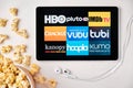 Movies application logo on the screen of the tablet laying on the white table and sprinkled popcorn on it. Apple Royalty Free Stock Photo