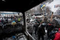 Moving activists walk past the barricades with police squads behind on the occupying snow street during anti-government protest