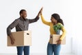 Moving Day. Joyful Black Spouses Holding Cardboard Boxes And Giving High Five Royalty Free Stock Photo