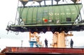 Moving freight railway car in the port by a port crane. Cargo lifting operations. Industrial port