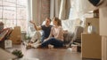 Moving In: Happy Couple Talk, Sitting on a Living Room floor of their New Cozy Home. Cheerful Young Royalty Free Stock Photo