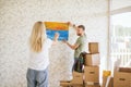 Moving house. Couple hanging picture on wall in new home Royalty Free Stock Photo