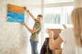 Moving house. Couple hanging picture on wall in new home Royalty Free Stock Photo