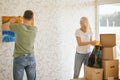 Moving house. Couple hanging picture on wall in new home Royalty Free Stock Photo