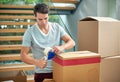 Moving house involves a lot of hard work. a young man packing up his belongings into boxes before moving out. Royalty Free Stock Photo