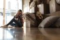 Moving out. Woman listening to music with wireless headphones next to stack of cardboard boxes in front of window Royalty Free Stock Photo