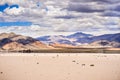 Moving rocks scattered around the surface of the Racetrack Playa; mountains and clouds scenery in the background; Death Valley Royalty Free Stock Photo