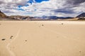 Moving rocks and their tracks at the Racetrack Playa; mountains and clouds scenery in the background; Death Valley National Park, Royalty Free Stock Photo