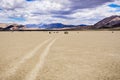 Moving rocks and their tracks at the Racetrack Playa; mountains and clouds scenery in the background; Death Valley National Park, Royalty Free Stock Photo