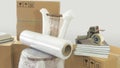 Moving scene with a roll of plastic to pack on a chair wrapped in plastic with closed cardboard boxes, books and masking tape on