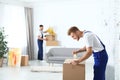 Moving service employee sealing cardboard box with adhesive tape Royalty Free Stock Photo