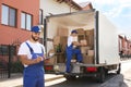 Moving service workers outdoors, unloading boxes and checking list Royalty Free Stock Photo