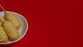 Moving shot of red background with white plate and five corn dogs with sauce.