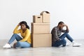 Moving Stress Concept. Upset Black Couple Sitting Next To Cardboard Boxes