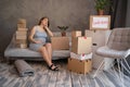 moving to a new apartment. young pregnant woman with cardboard boxes sitting on sofa, housing program Royalty Free Stock Photo