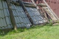 Mowed-down and fallen fence of wooden logs connected by planks to which sheets of old ceramic gray slate are fixed Royalty Free Stock Photo