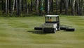 Mower work in the grass at the edge of a Scottish golf course. Machine for turf on Golf Royalty Free Stock Photo